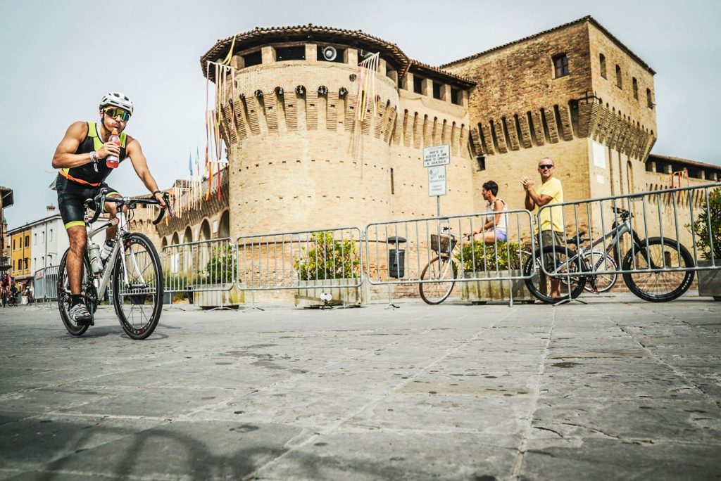 a man riding a bike down a street next to a tall building