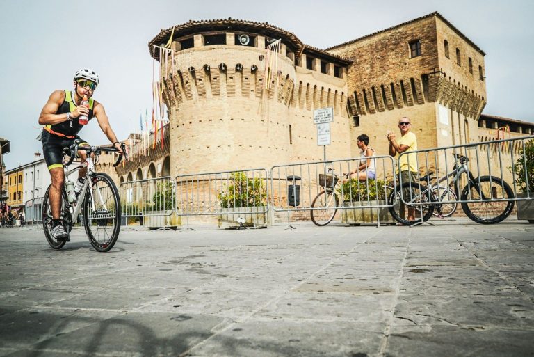 a man riding a bike down a street next to a tall building